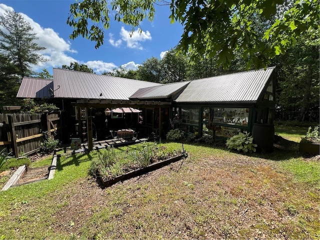 rear view of house featuring metal roof and a garden