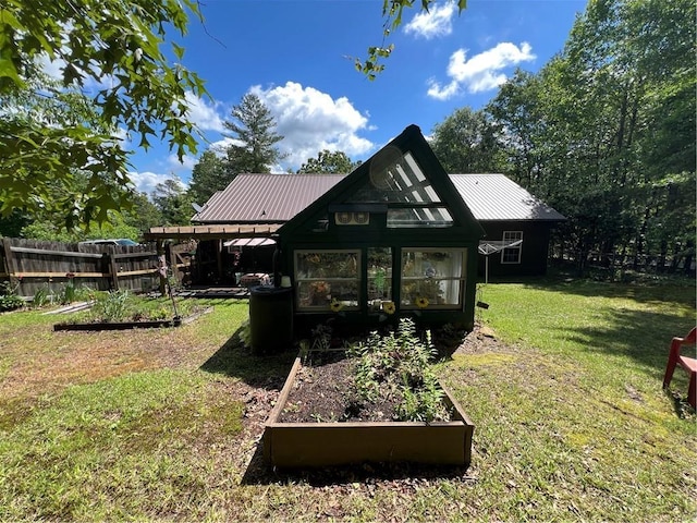 back of property featuring a vegetable garden and metal roof