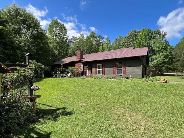 view of front of house featuring a front lawn, metal roof, and a chimney