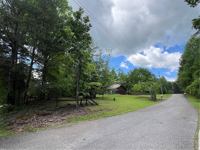 view of asphalt street featuring view of wooded area