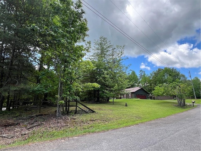 view of green lawn featuring an attached garage and view of wooded area