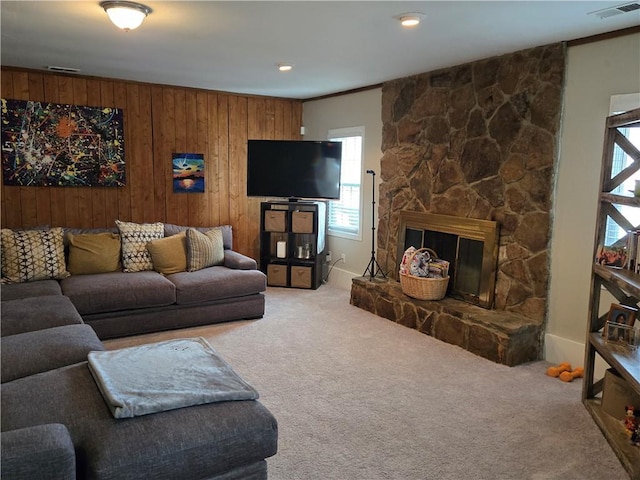 living room with a fireplace, wooden walls, and carpet