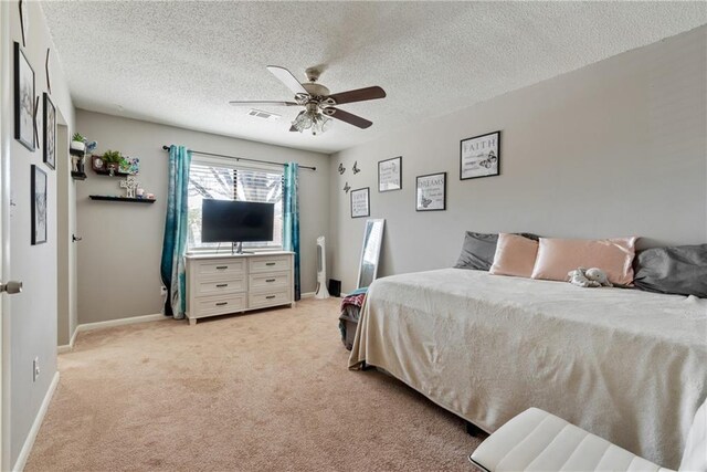 bedroom with light carpet, baseboards, visible vents, and a textured ceiling