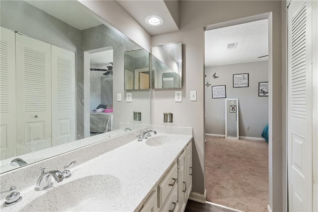 ensuite bathroom featuring a closet, visible vents, a sink, and double vanity