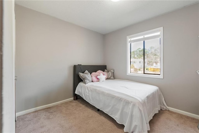 bedroom with light colored carpet and baseboards