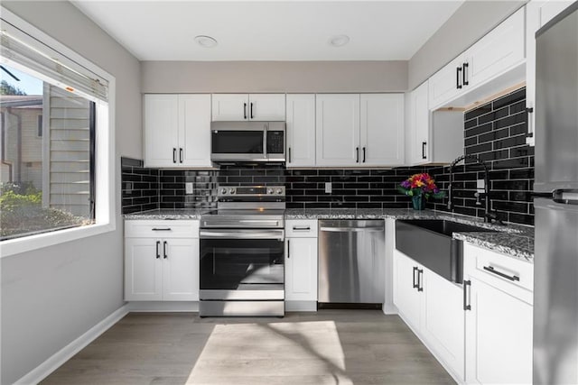 kitchen with appliances with stainless steel finishes, white cabinetry, and plenty of natural light