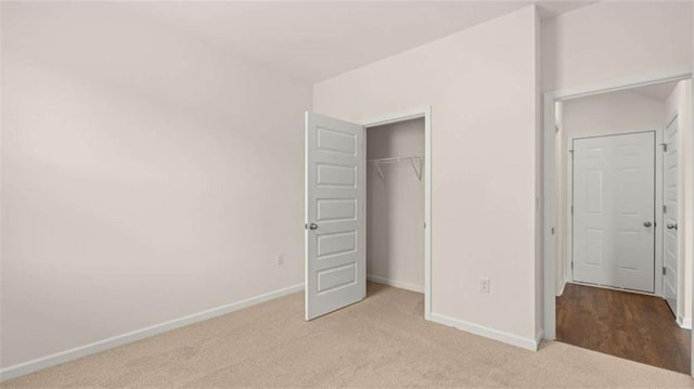 unfurnished bedroom featuring light colored carpet and a closet