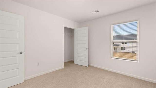 unfurnished bedroom with light carpet and a closet