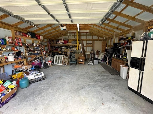 garage with a garage door opener and white refrigerator with ice dispenser