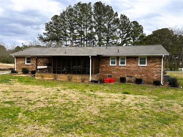 rear view of house with a sunroom, brick siding, and a yard