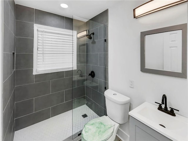 bathroom with vanity, toilet, and a tile shower