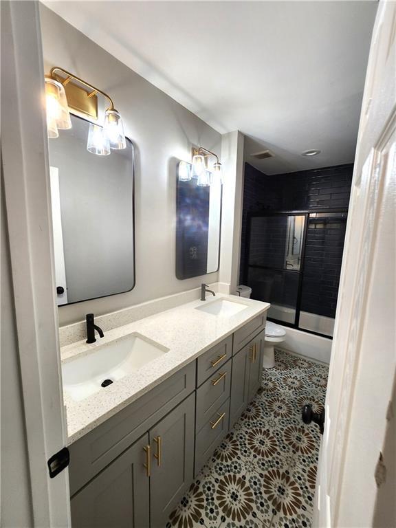 full bathroom featuring toilet, tile patterned flooring, vanity, and combined bath / shower with glass door