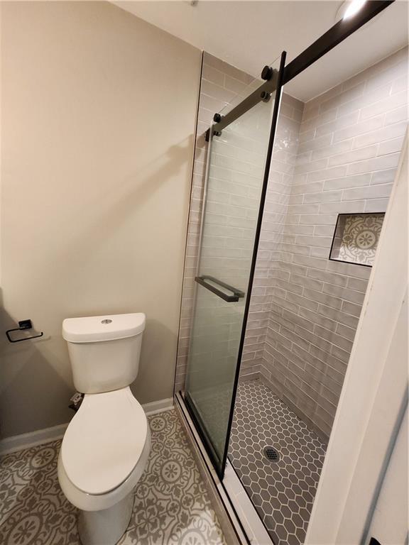 bathroom featuring walk in shower, tile patterned flooring, and toilet