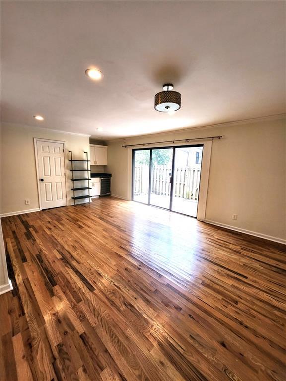 unfurnished living room with crown molding and hardwood / wood-style floors