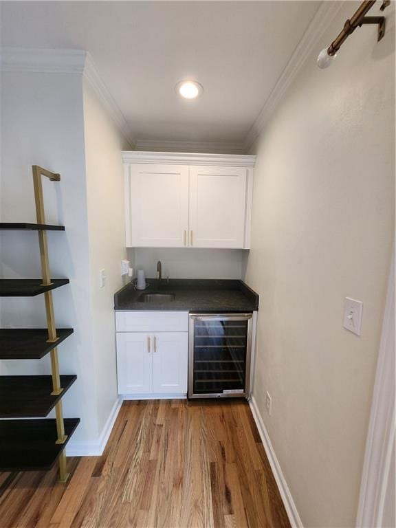 bar with hardwood / wood-style flooring, wine cooler, white cabinets, ornamental molding, and sink