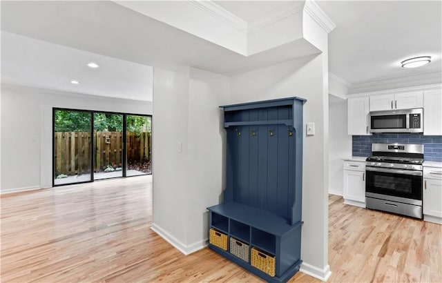 kitchen with stainless steel appliances, white cabinetry, crown molding, and decorative backsplash