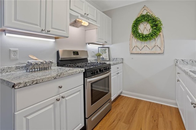 kitchen with baseboards, light wood-type flooring, white cabinetry, under cabinet range hood, and gas stove