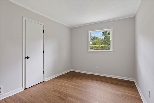 spare room featuring baseboards, ornamental molding, and wood finished floors