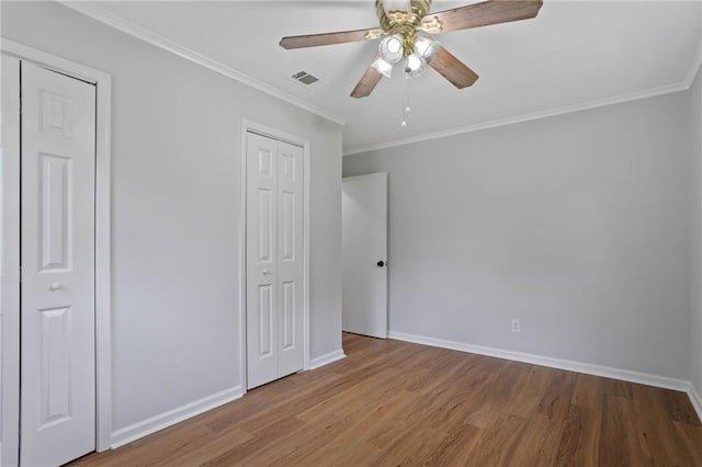unfurnished bedroom with baseboards, visible vents, ornamental molding, and wood finished floors