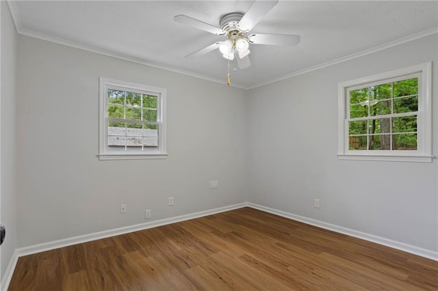 empty room with crown molding, baseboards, and wood finished floors