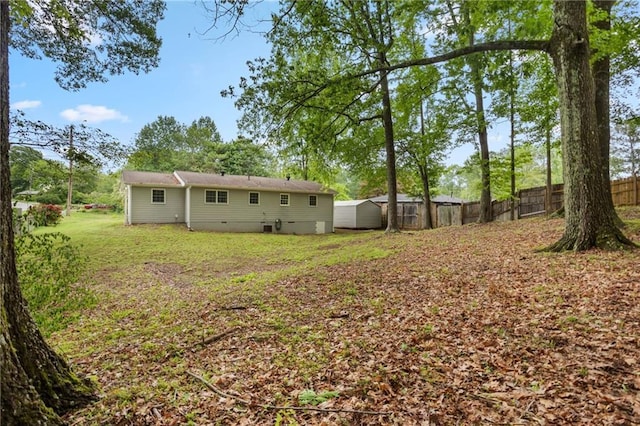 view of yard featuring fence, an outdoor structure, and a storage unit