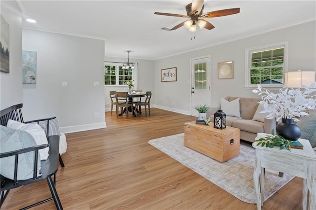 living room with crown molding, baseboards, and ceiling fan with notable chandelier