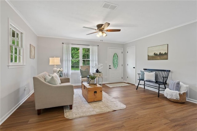 living room featuring crown molding, a ceiling fan, visible vents, and wood finished floors