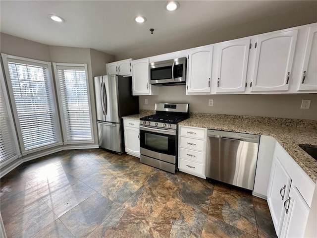 kitchen with white cabinets, light stone counters, and stainless steel appliances