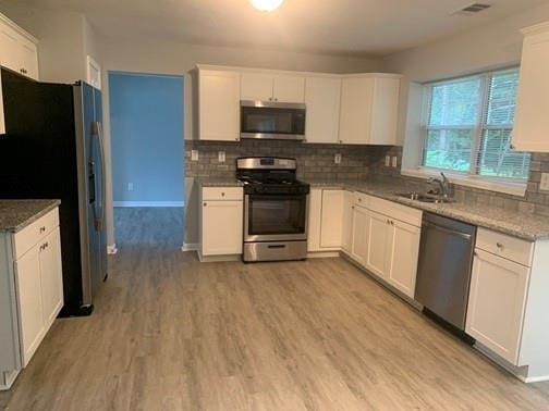 kitchen featuring light stone counters, sink, white cabinets, and stainless steel appliances