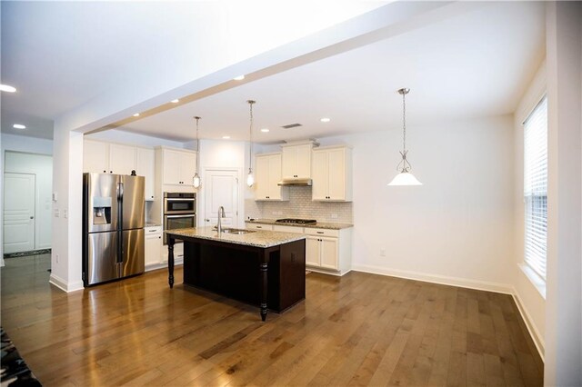 kitchen featuring sink, hanging light fixtures, dark hardwood / wood-style floors, an island with sink, and appliances with stainless steel finishes