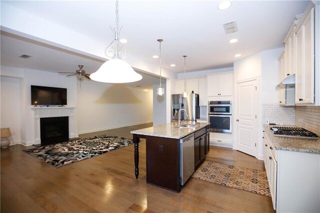 kitchen featuring white cabinetry, hanging light fixtures, hardwood / wood-style floors, a kitchen island with sink, and appliances with stainless steel finishes