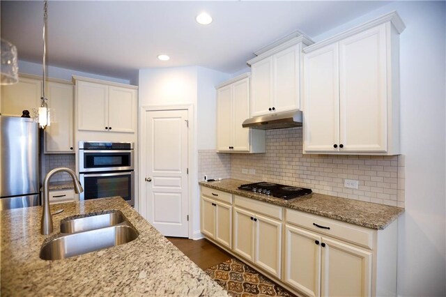 kitchen with light stone countertops, stainless steel appliances, tasteful backsplash, and sink