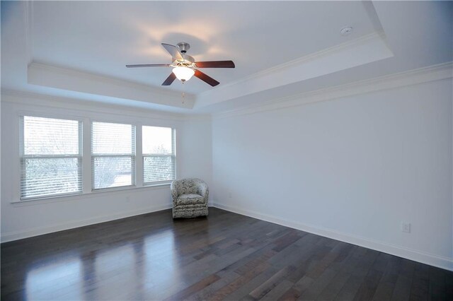 spare room with a tray ceiling, crown molding, ceiling fan, and dark hardwood / wood-style floors