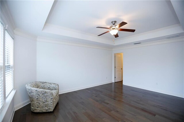 empty room with dark hardwood / wood-style floors, a tray ceiling, crown molding, and ceiling fan