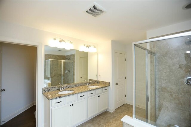 bathroom featuring tile patterned flooring, vanity, and a shower with shower door