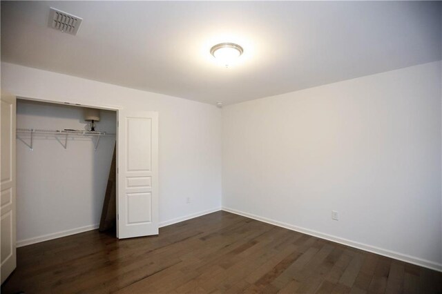 unfurnished bedroom with a closet and dark wood-type flooring