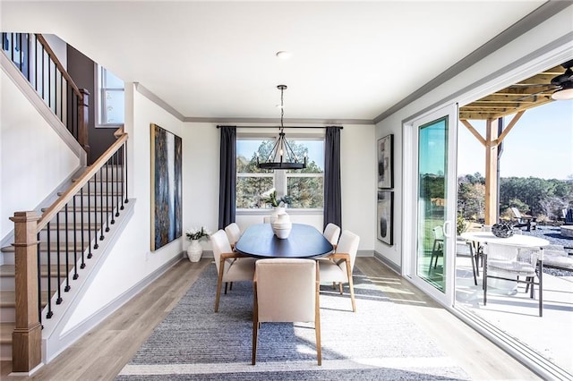 dining area with stairs, ornamental molding, baseboards, and light wood-style floors