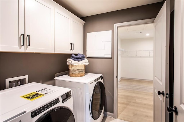 laundry room featuring light wood-style flooring, cabinet space, and washer and clothes dryer