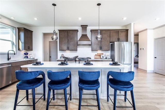 kitchen featuring wall chimney exhaust hood, a kitchen island, and light countertops