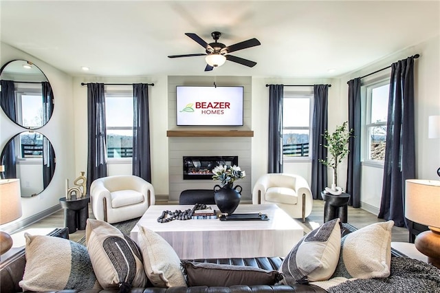 living area featuring baseboards, a healthy amount of sunlight, a fireplace, and light wood finished floors