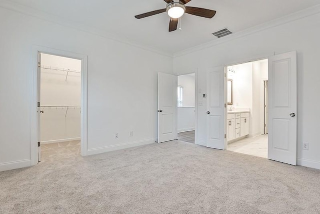 unfurnished bedroom with ornamental molding, a spacious closet, light colored carpet, ceiling fan, and a closet