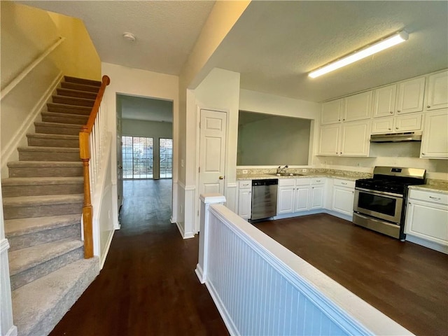 kitchen with sink, dark wood-type flooring, white cabinetry, stainless steel appliances, and a textured ceiling