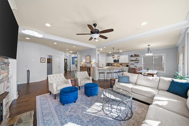 living room featuring a stone fireplace, ceiling fan, dark hardwood / wood-style flooring, and ornamental molding