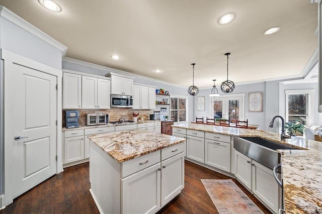 kitchen with appliances with stainless steel finishes, sink, dark hardwood / wood-style floors, white cabinetry, and hanging light fixtures