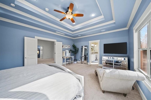 carpeted bedroom featuring a tray ceiling, ceiling fan, crown molding, and ensuite bathroom