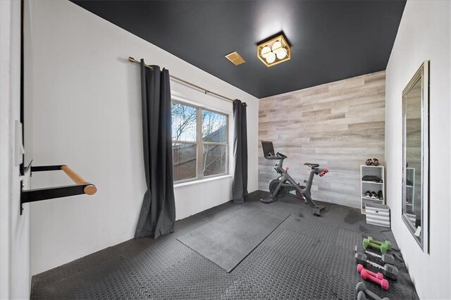 workout area with wooden walls and dark carpet