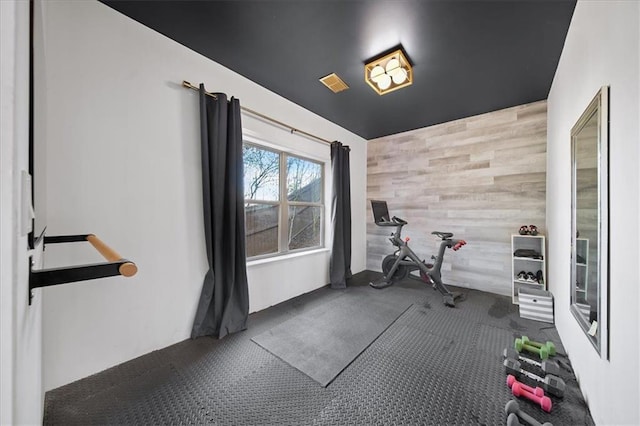 exercise area with dark carpet and wooden walls