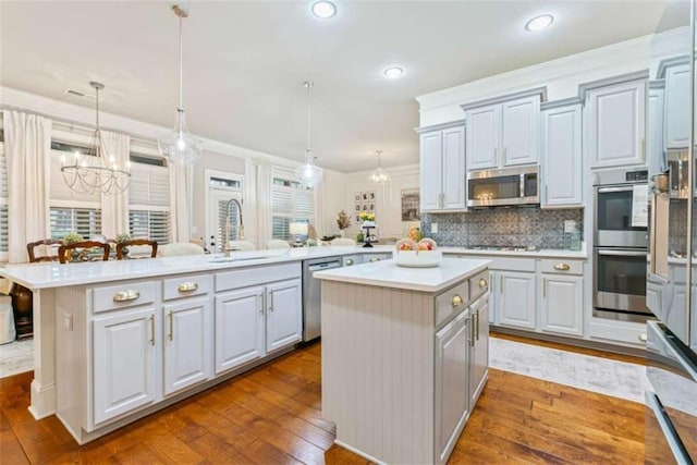 kitchen with light countertops, appliances with stainless steel finishes, a sink, and a center island with sink