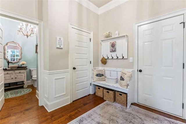 mudroom with dark wood-type flooring, a wainscoted wall, a notable chandelier, and crown molding