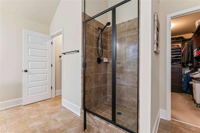 bathroom with a stall shower, tile patterned flooring, a spacious closet, and baseboards